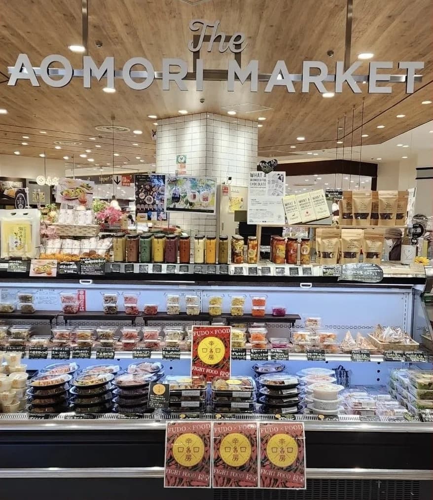 The AOMORI MARKETの看板の下に惣菜と弁当が並ぶ売場